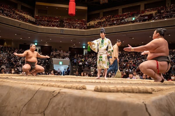 Two sumo wrestler and one referee on stage