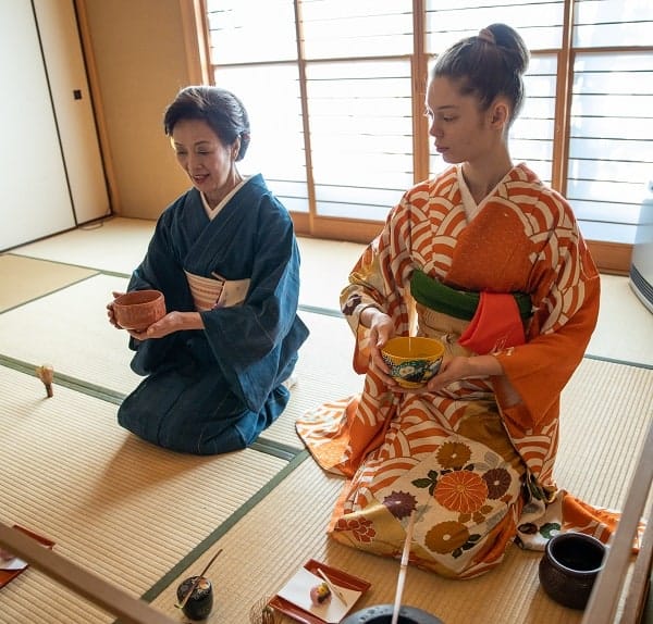 Japanese woman teaching woman how to hold the tea properly