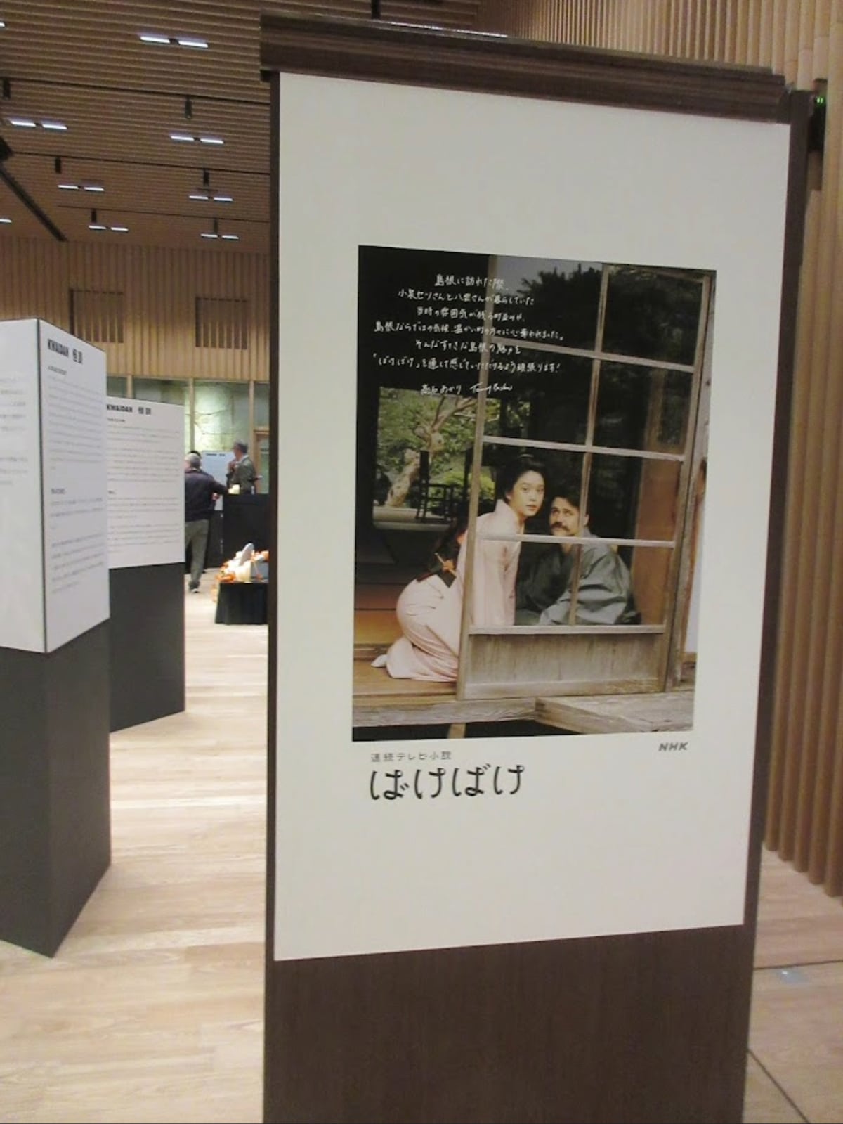 A display panel featuring a photo of actors from the morning drama "Bake Bake" representing Lafcadio Hearn and his wife Setsu.