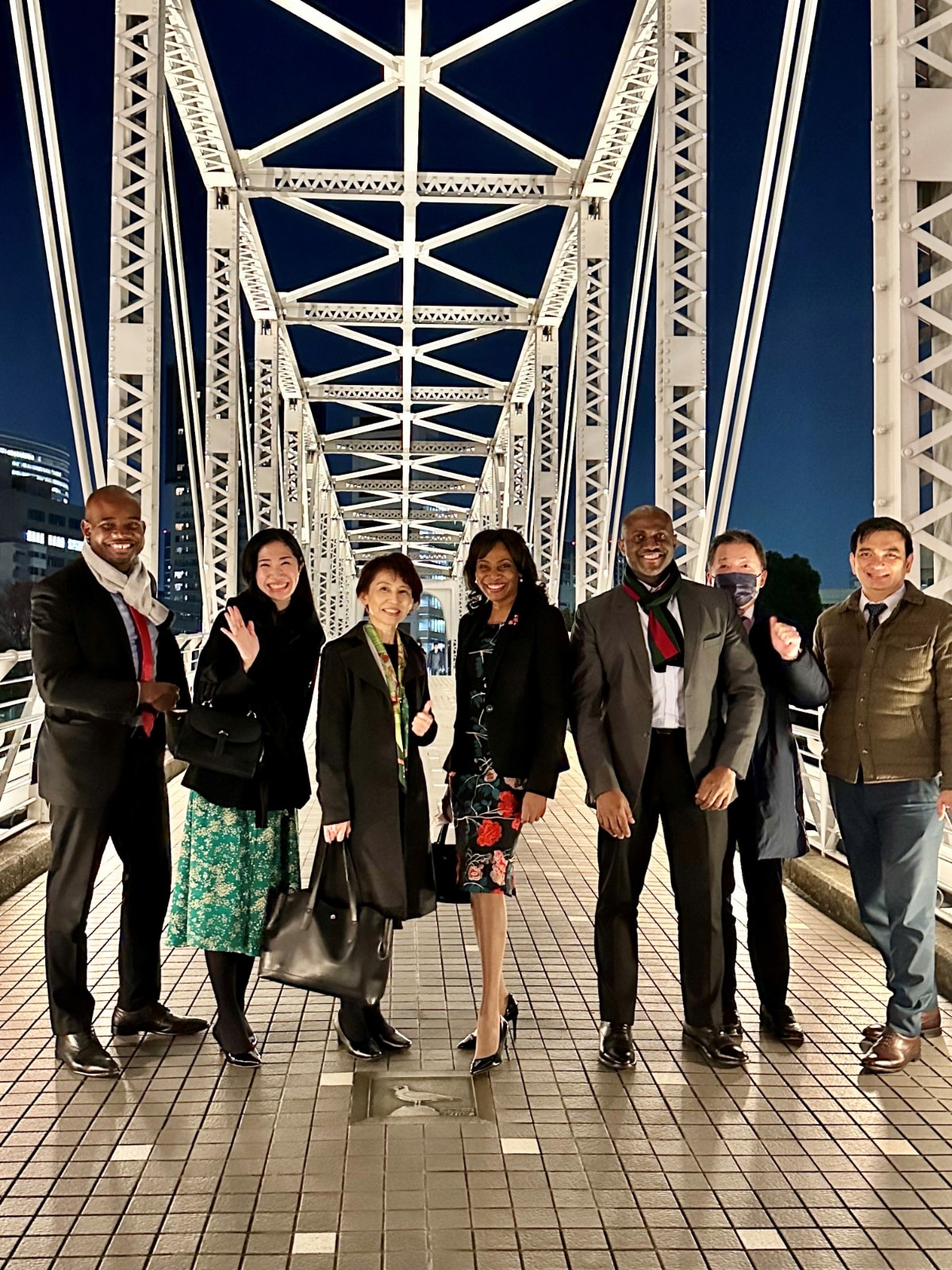 Ambassador Shorna-Kay Richards and her embassy team posing together on a bridge at night in Japan, representing their unified diplomatic mission.