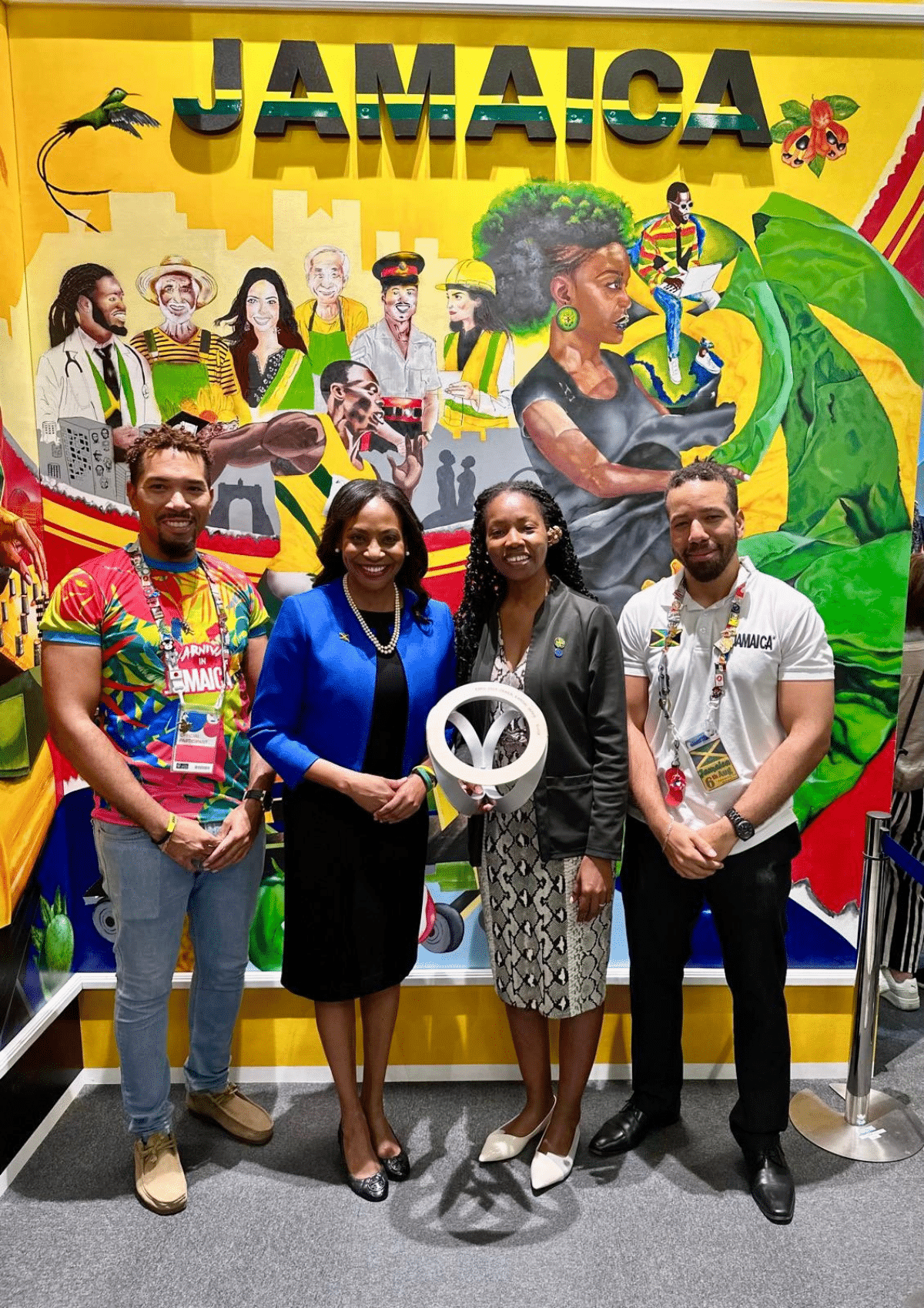 Ambassador Shorna-Kay Richards and colleagues standing in front of a colorful "JAMAICA" mural, symbolizing the lasting cultural bond and legacy of her diplomatic mission in Japan.