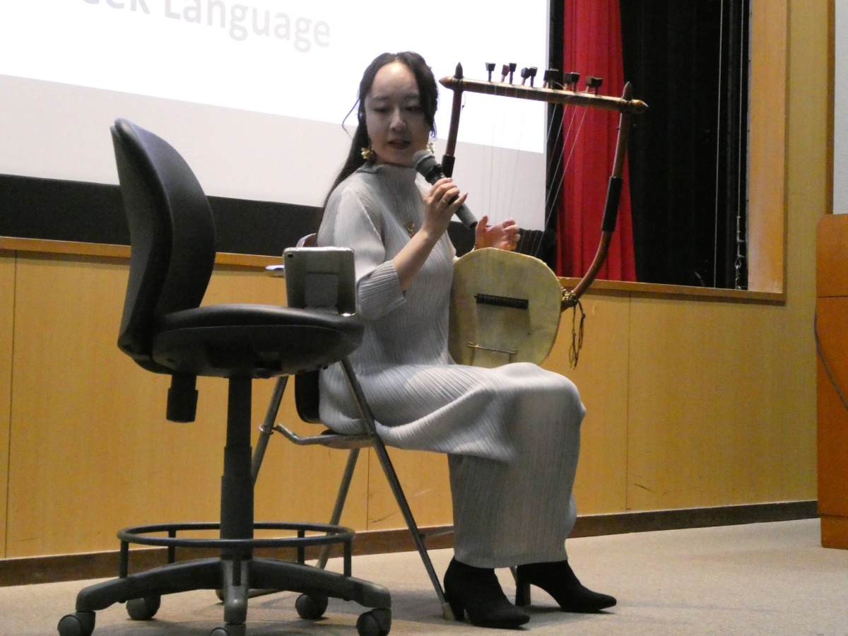 A musician performing with a recreated ancient Greek string instrument during the commemorative lecture.