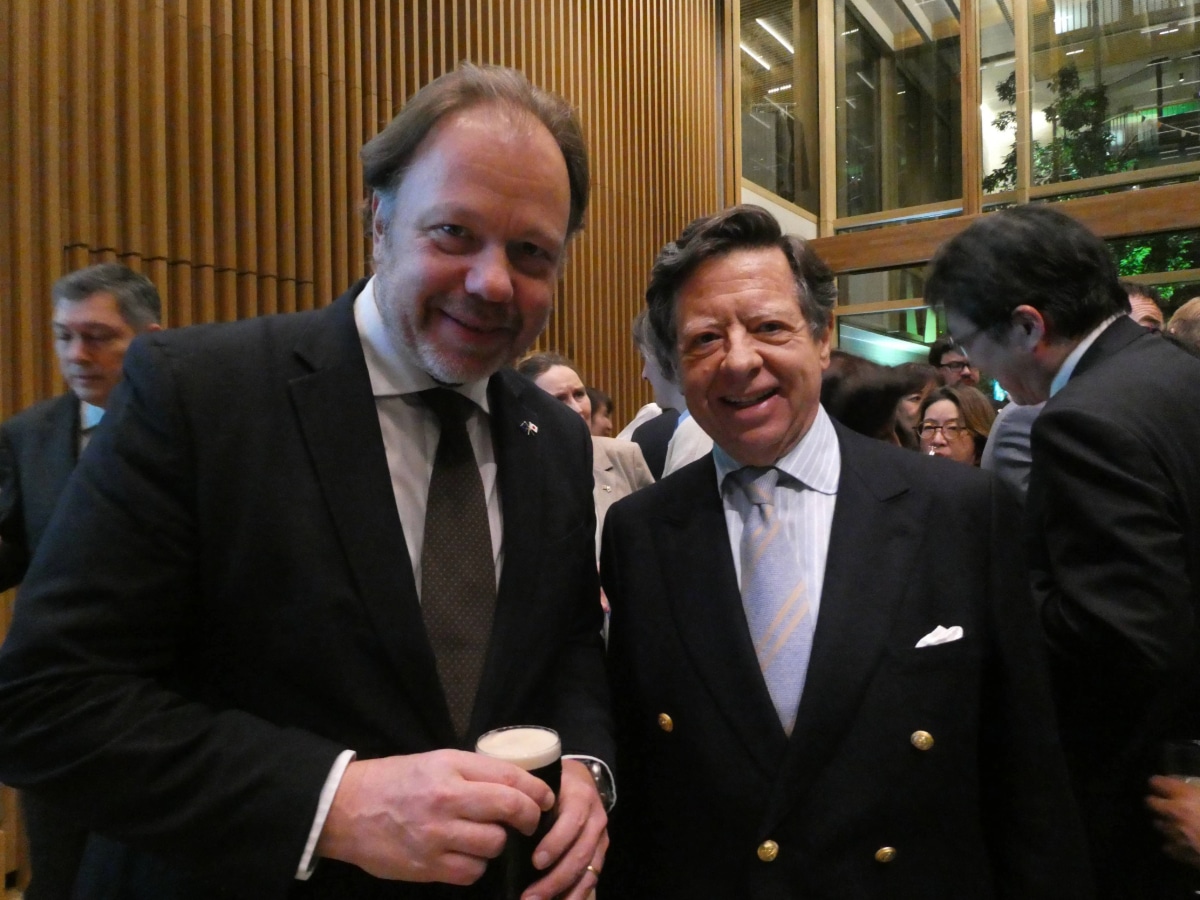Guests and dignitaries networking inside the modern, wood-paneled hall of the new Irish Embassy during a cultural reception.