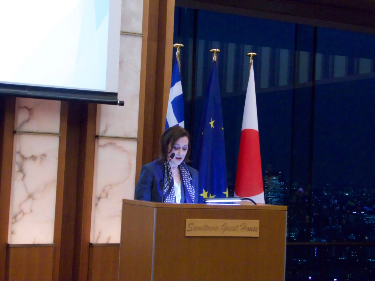 H.E. Olga Kliamaki, Greek Ambassador to Japan, speaking at the podium with Greek, EU, and Japanese flags during the National Day Reception.
