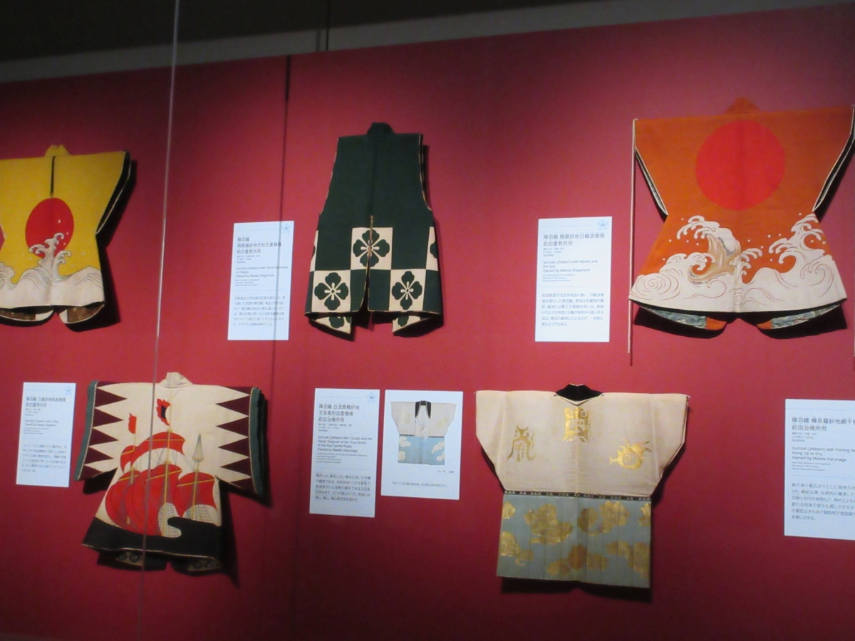 A display of colorful and innovative jinbaori (warrior surcoats) with bold patterns and sun motifs.