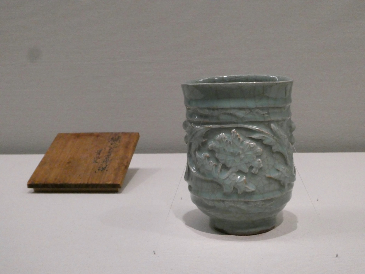 Celadon-glazed vessel with a relief peony design and a wooden lid, displayed at the Kawai Kanjiro exhibition