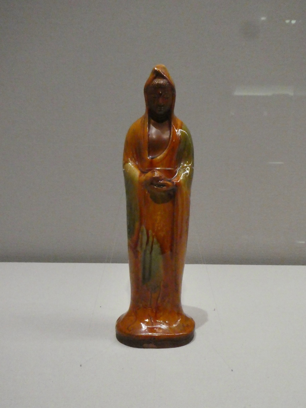 Standing hooded ceramic figure with amber and green glaze at the Seikado Bunko Art Museum exhibition