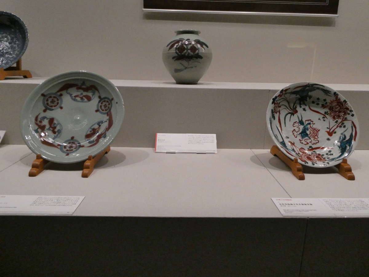 Porcelain dishes and a vase with red and blue floral decoration displayed at the Kawai Kanjiro exhibition