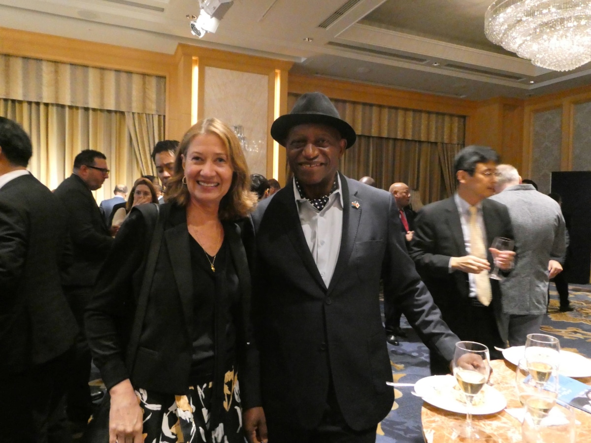 Two guests smile for a photo at the Armenia Independence Day reception, with wine glasses on a nearby table