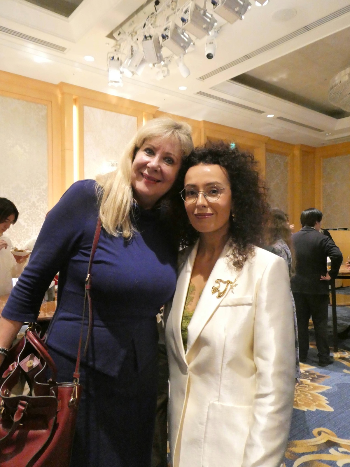 Two women pose cheek to cheek in a friendly embrace at the Armenia Independence Day reception