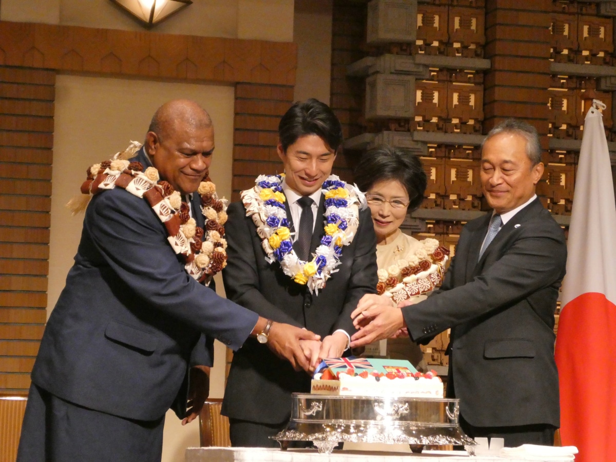 Guests wearing leis cut the Fiji Independence Day cake together at the reception in Japan