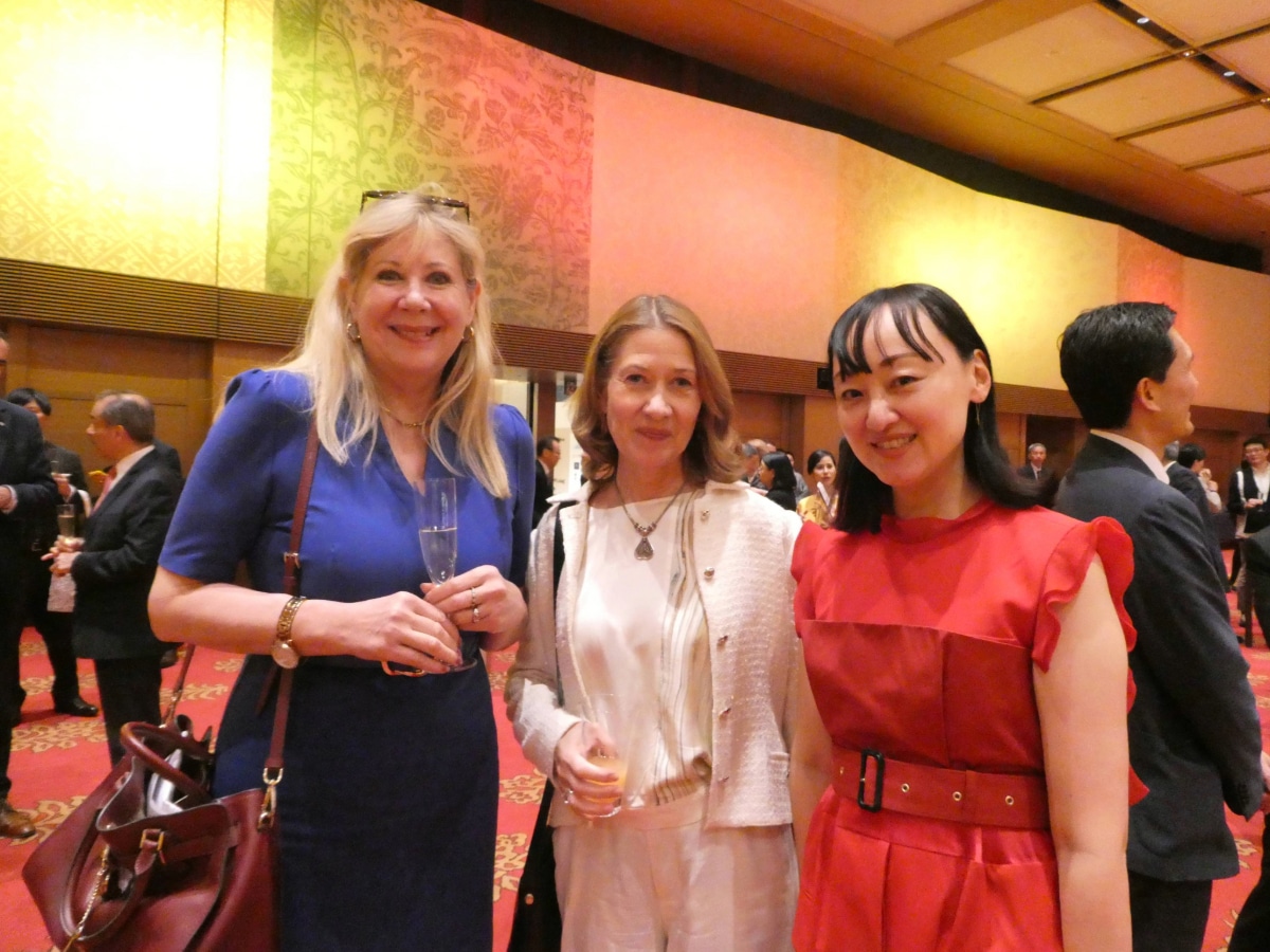 Three smiling guests with drinks at the Spain National Day reception in Japan