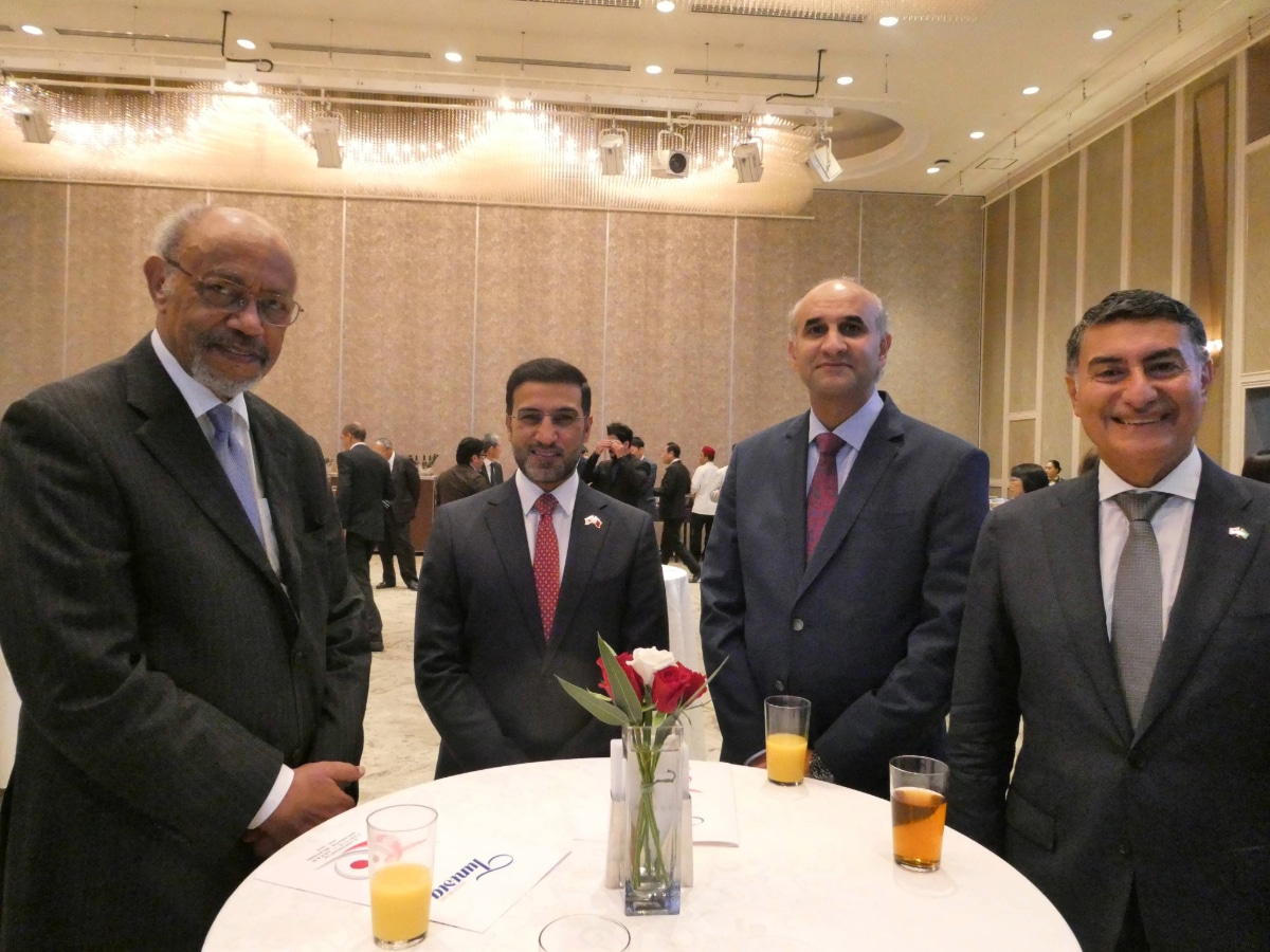 Four men in suits standing around a cocktail table with red roses at the Tunisia-Japan anniversary reception