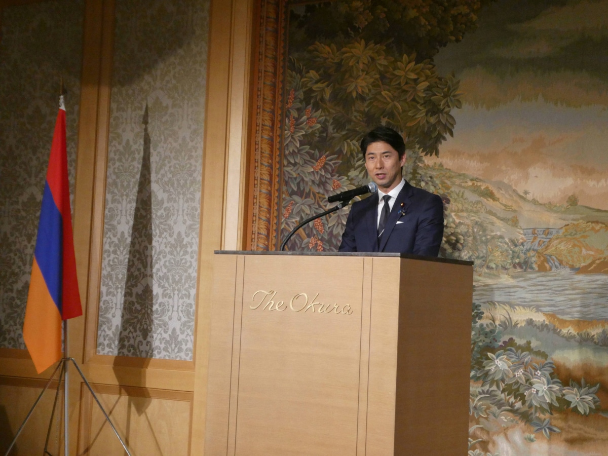 A man in a navy suit speaks at the podium beside the Armenian flag at the Armenia Independence Day reception