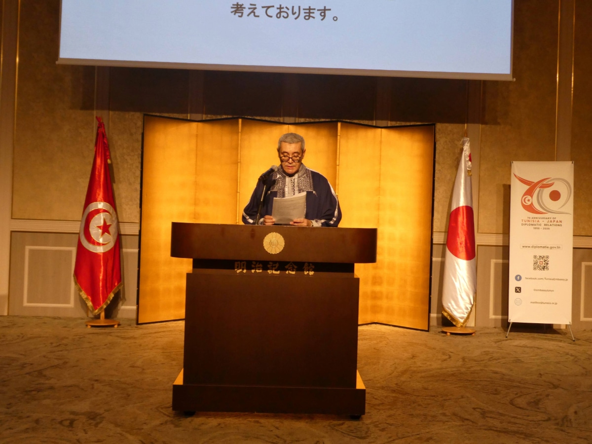 Speaker at the podium between the Tunisian and Japanese flags at the reception marking 70 years of Tunisia-Japan diplomatic relations in Tokyo