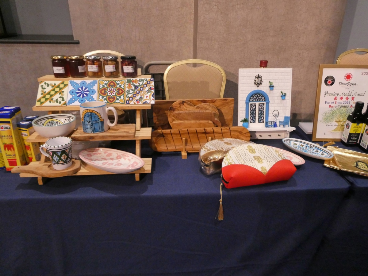 Display table of Tunisian handicrafts including painted tiles, ceramics, olive wood items and a decorative blue-door house piece